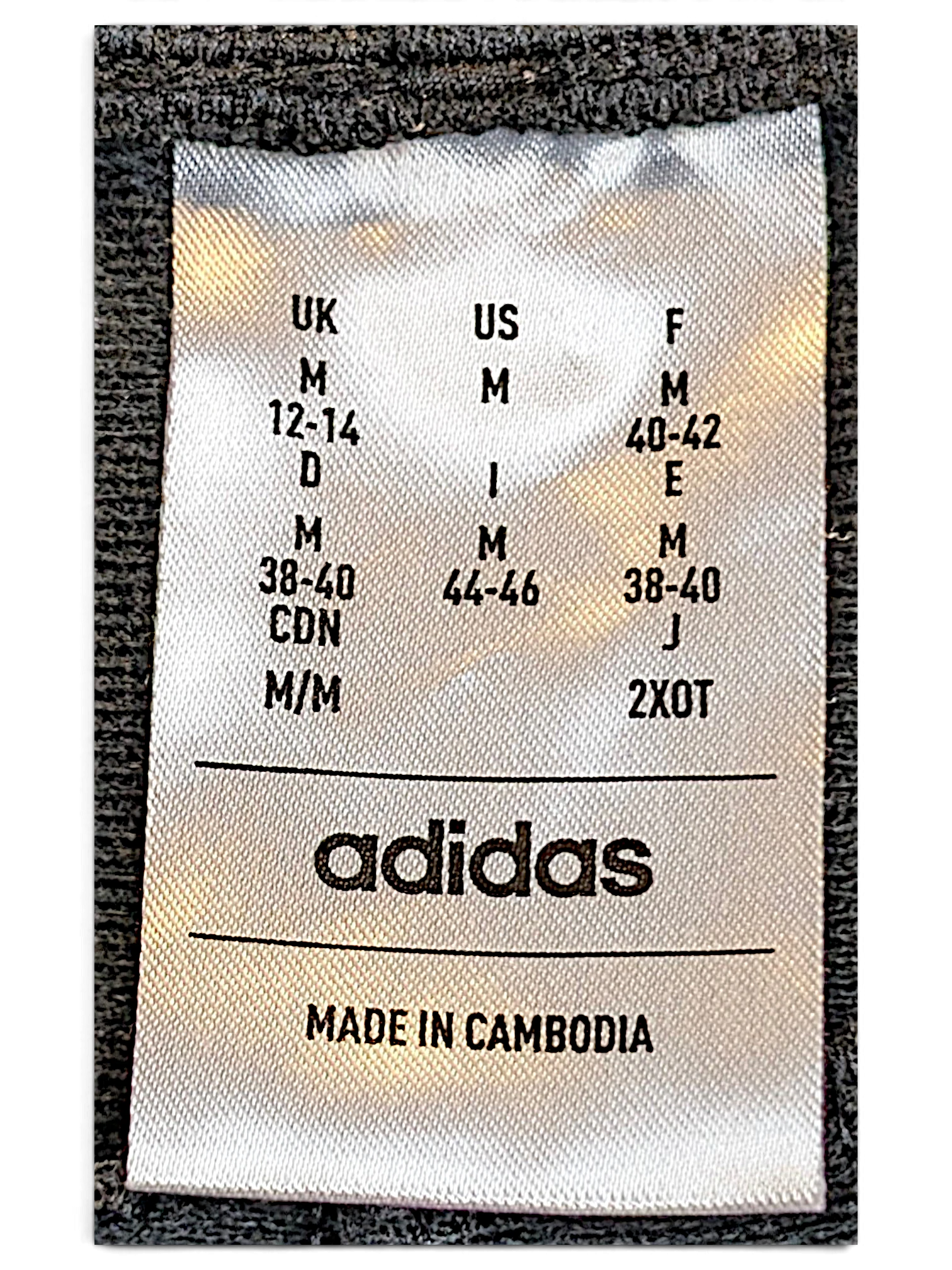 JAKE & IPI adidas track pants size M clothing label showing international sizing and made in Cambodia details