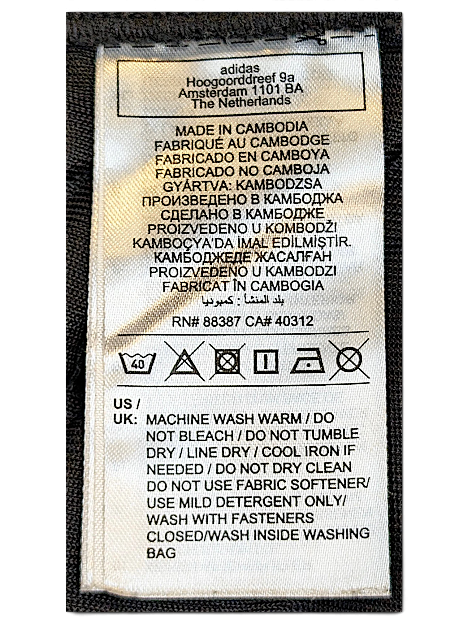 JAKE & IPI adidas track pants care label with washing instructions and manufacturing details in Cambodia