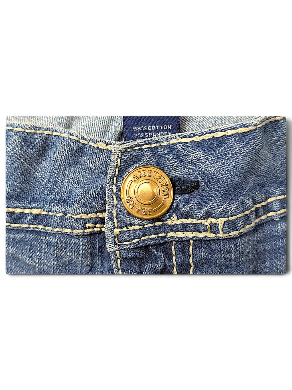 JAKE & IPI Amethyst Y2K jeans featuring a gold-tone branded button and contrast stitching on blue denim fabric.