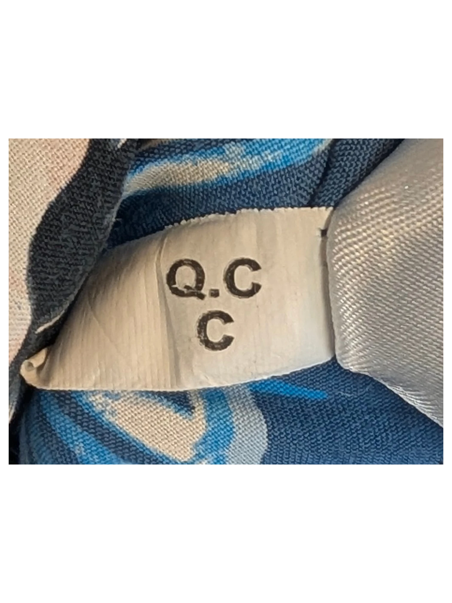 JAKE & IPI Angelo Litrico Hawaiian shirt fabric detail showing a Q.C.C quality control tag on blue patterned fabric