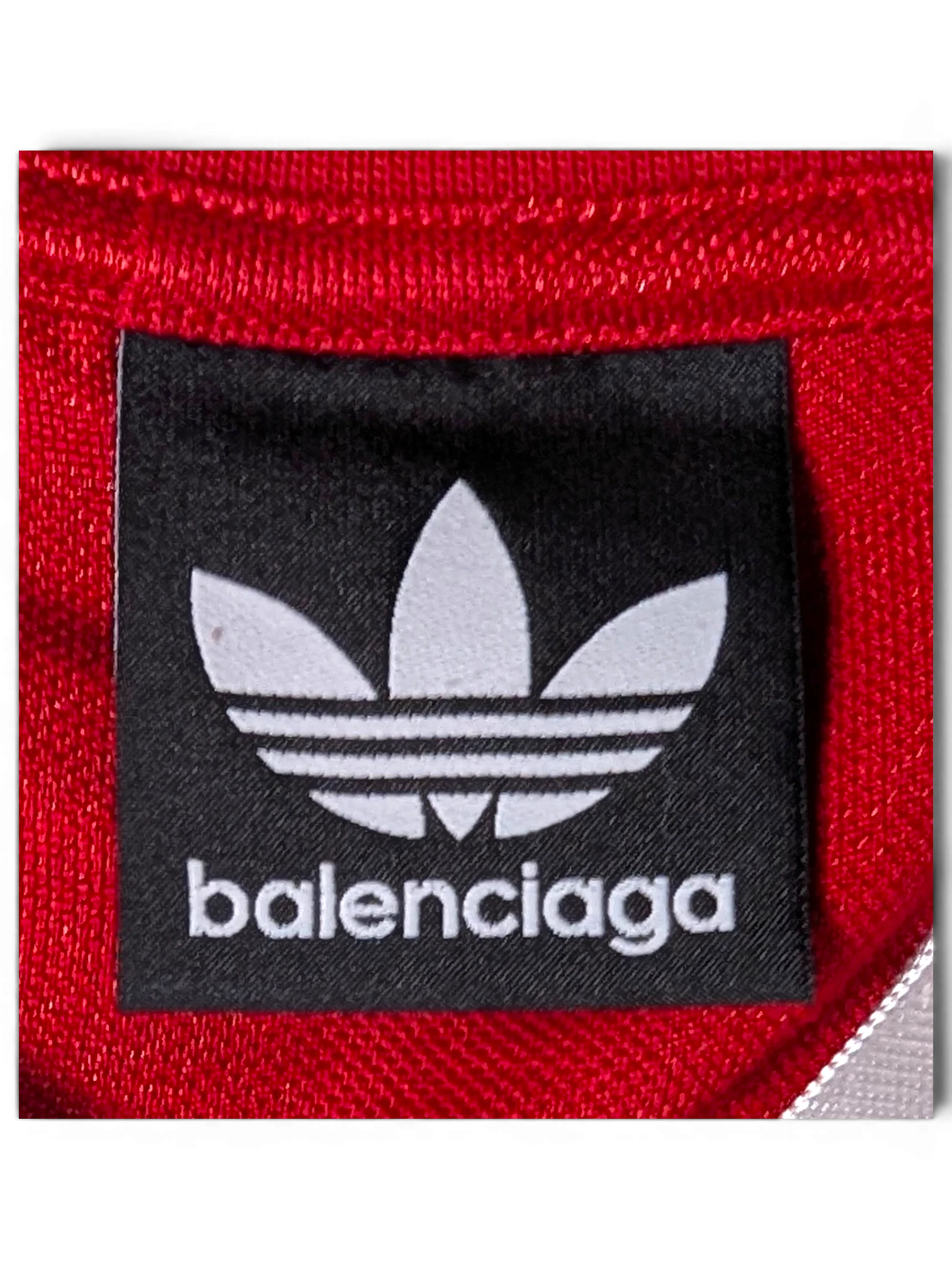 JAKE & IPI Balenciaga x Adidas red jersey featuring a black brand label with the iconic trefoil logo