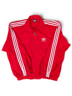 JAKE & IPI Balenciaga x Adidas red zip-up track jacket with white three-stripe detailing and dual branding.