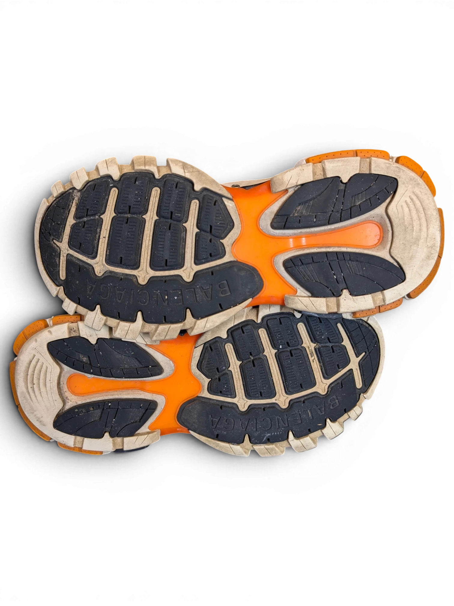JAKE & IPI Balenciaga Track sneakers featuring a white, grey, and orange rugged rubber outsole on a black background.