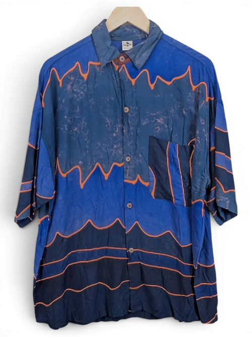 JAKE & IPI Bali Eva Hawaiian shirt in blue with orange wave patterns and a chest pocket hanging on a hanger
