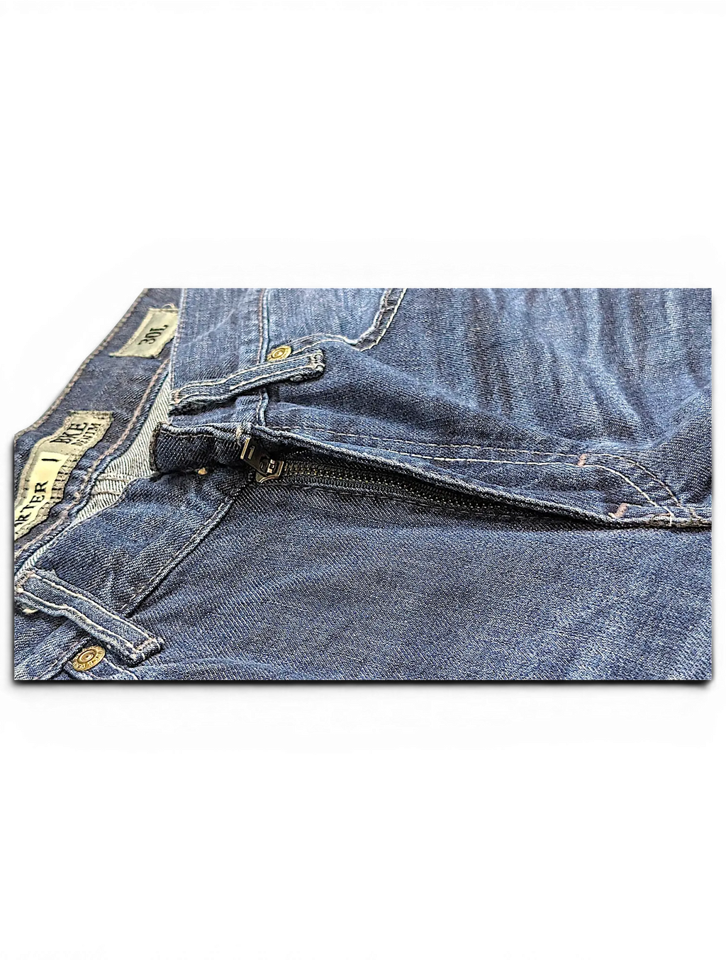 Close-up of JAKE & IPI BKE Denim Carter 30L blue jeans featuring a metal zipper fly and branded rivets.