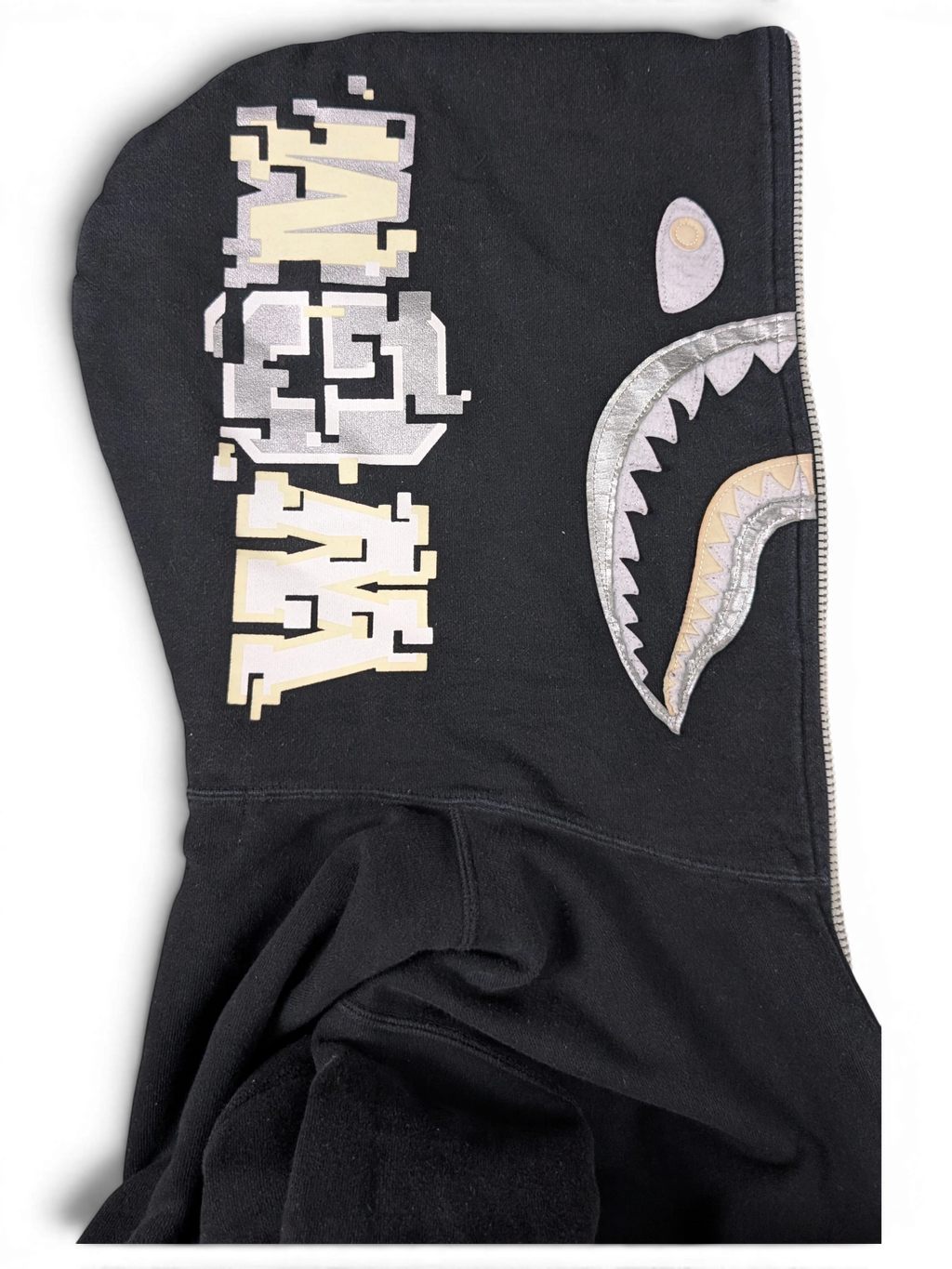 JAKE & IPI black cotton Bape shark hoodie with metallic silver and cream pixelated graphic details on the hood