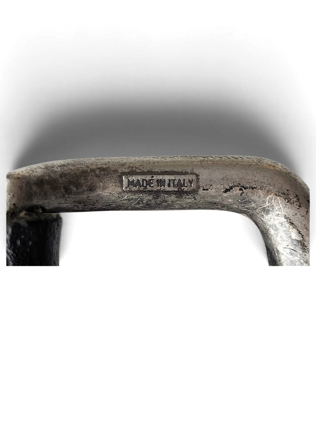 Close-up of a JAKE & IPI Bernd Götz black belt buckle with a distressed silver finish and Made in Italy engraving.