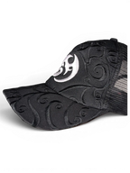 JAKE & IPI black trucker cap featuring intricate tonal swirl embroidery and a white circular logo on the front panel.