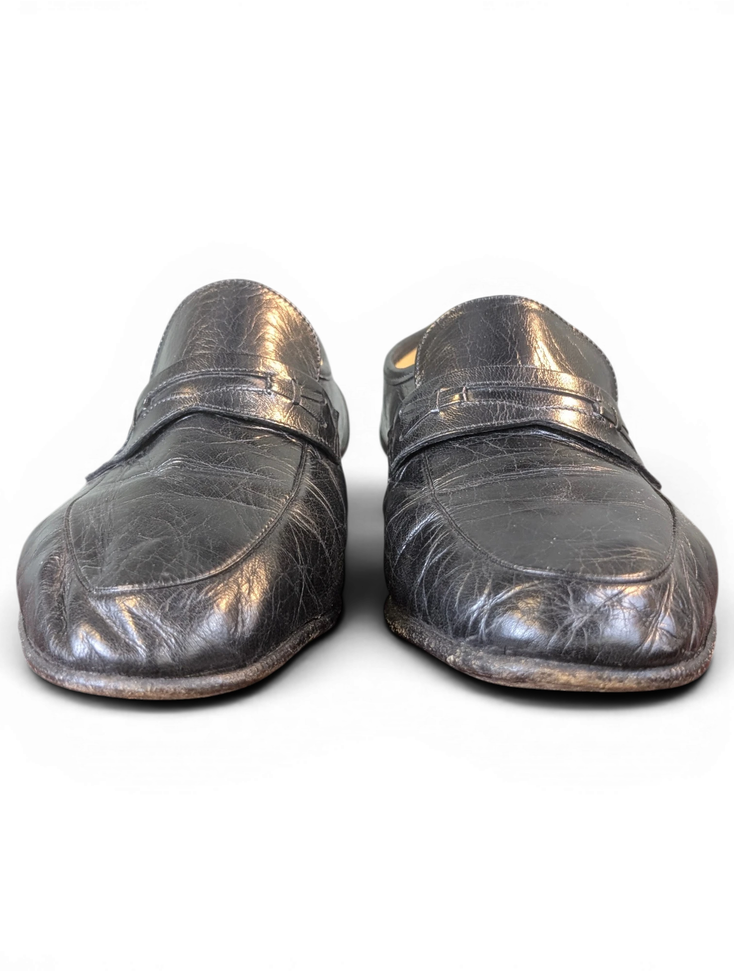 JAKE & IPI black leather penny loafers with a textured finish displayed on a wooden surface.