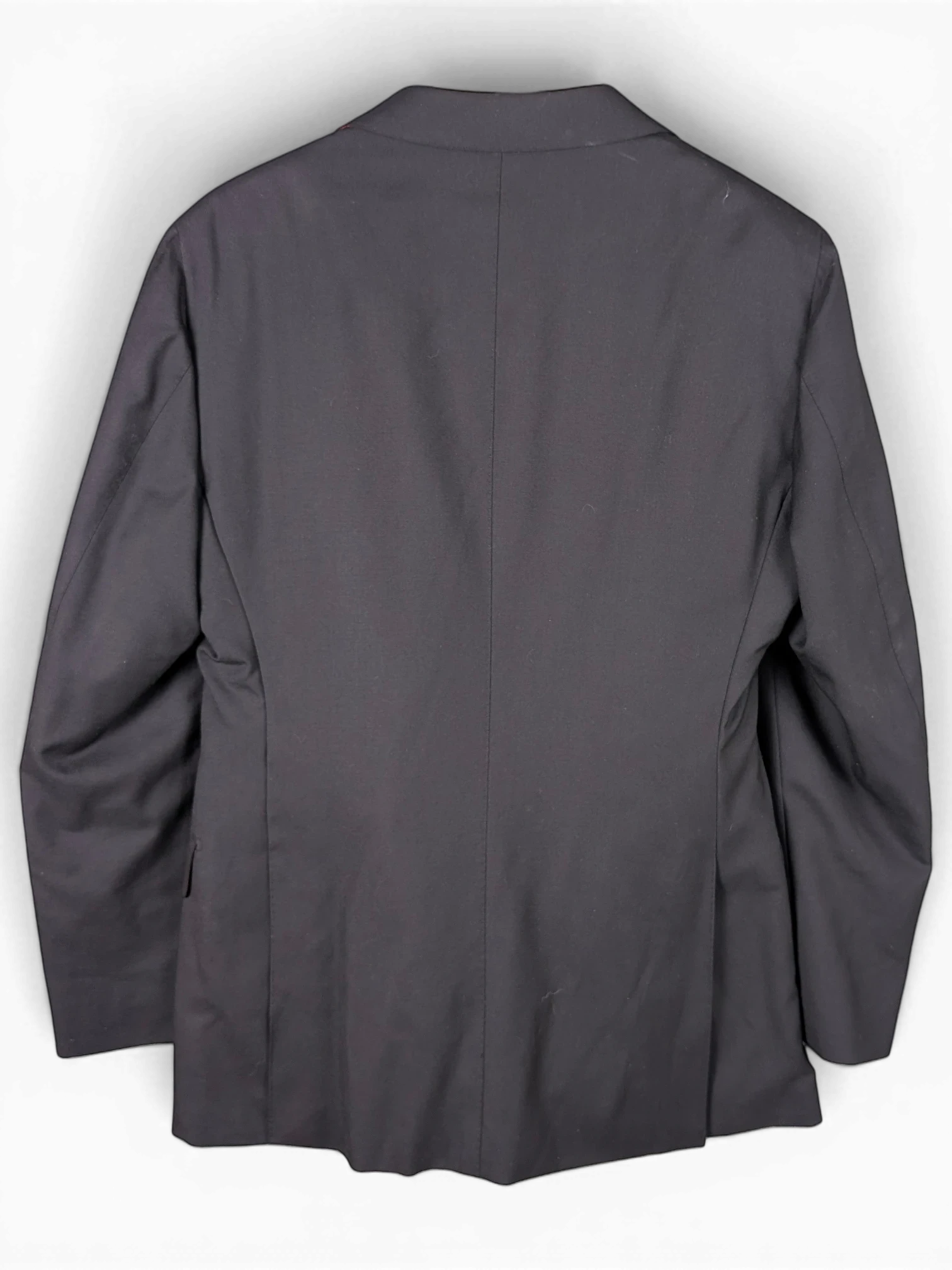 Back view of a black Suitsupply suit jacket hanging on a wooden hanger from JAKE & IPI