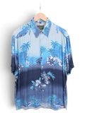 JAKE & IPI Destination Liberté blue Hawaiian shirt with tropical palm tree and floral print on a wooden hanger