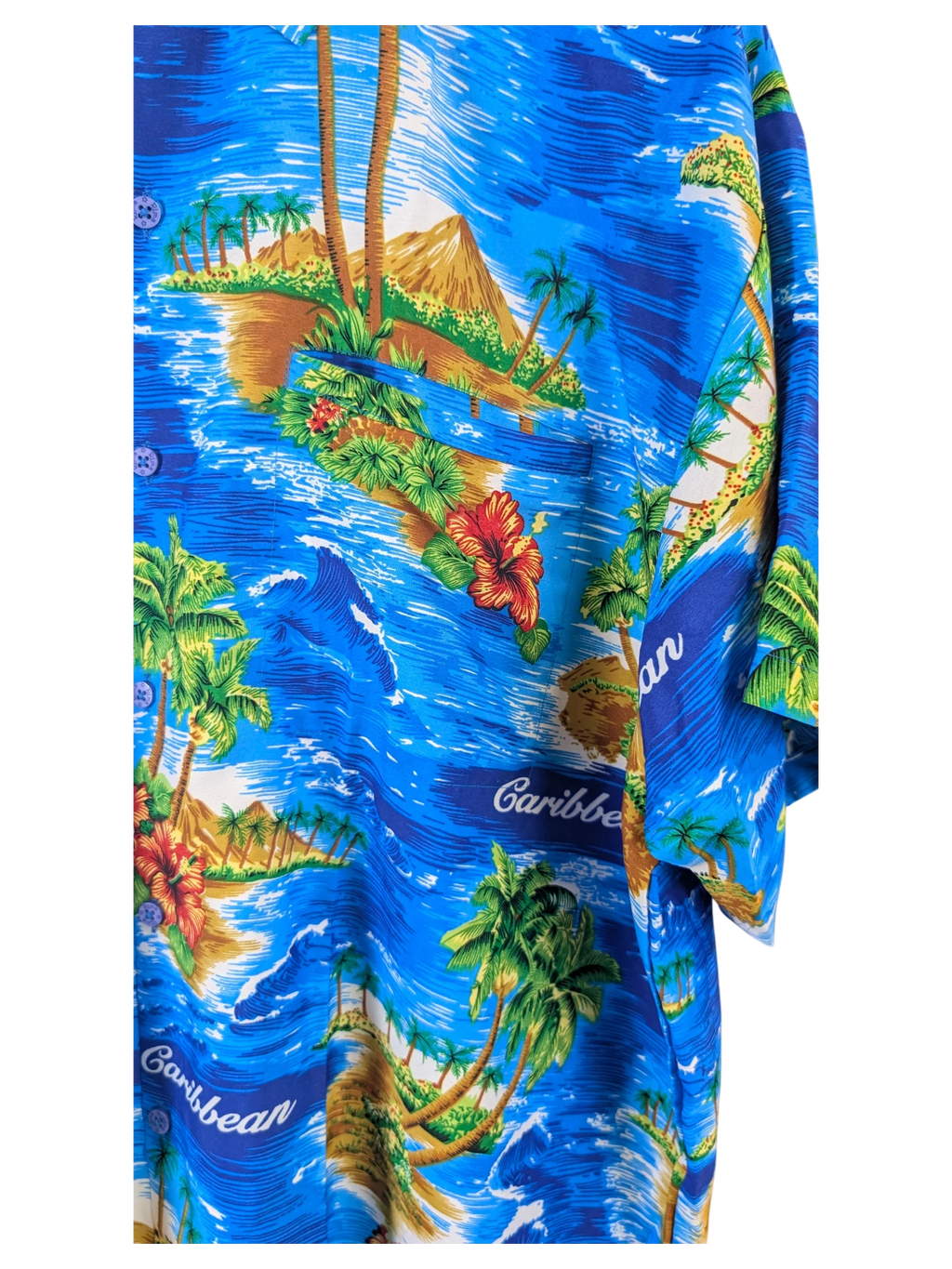 JAKE & IPI Rima Hawaiian shirt in blue featuring a vibrant tropical island print with palm trees and hibiscus flowers.