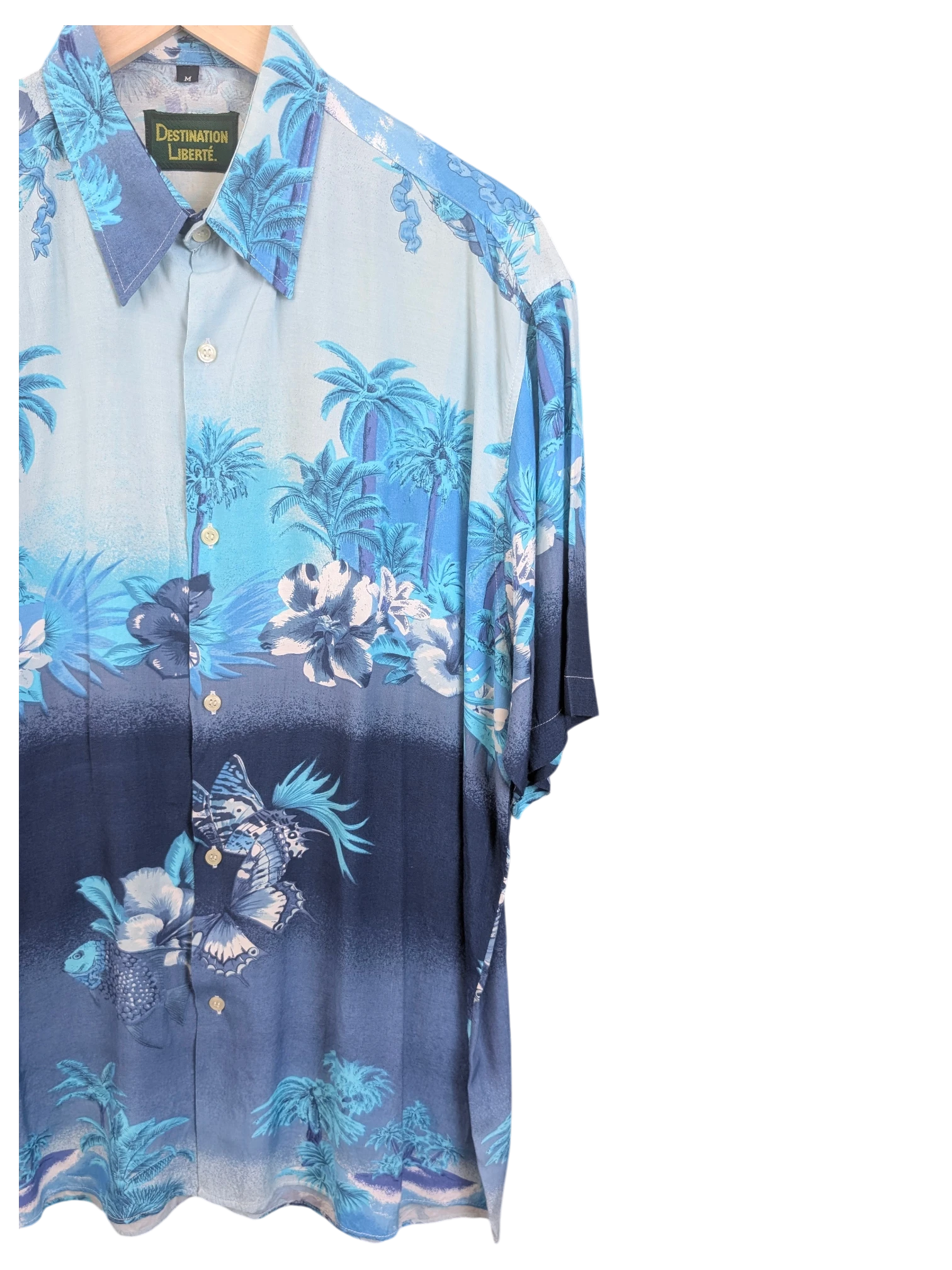 JAKE & IPI Destination Liberté Hawaiian shirt featuring a blue tropical palm tree and butterfly print on a gradient