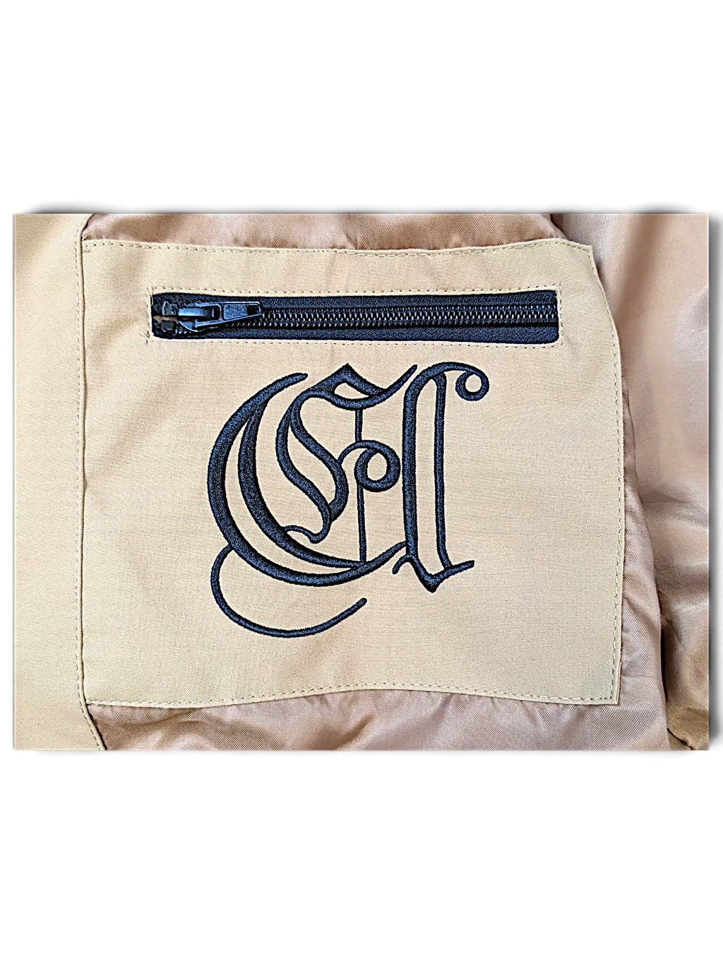 JAKE & IPI IBE Elenyor brown jacket interior pocket featuring a black embroidered logo and a secure zipper closure.