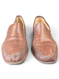 JAKE & IPI brown leather loafers with decorative whipstitch detailing on the toe, displayed on a wooden surface.