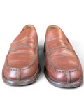 JAKE & IPI brown leather penny loafers with classic moccasin stitching on a wooden surface