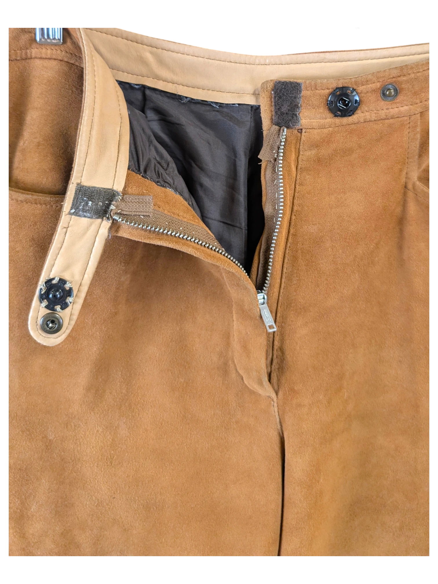JAKE & IPI Brandt brown suede reindeer leather pants with a front zipper and button closure hanging on a hanger.