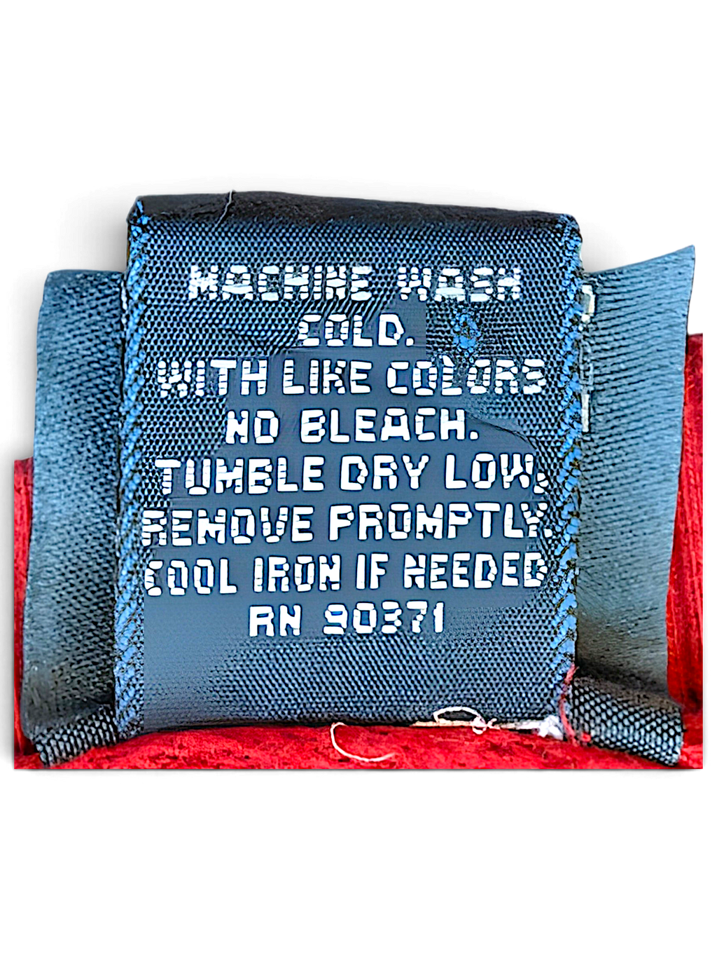 JAKE & IPI Camp David College clothing care label with washing instructions on a red fabric background