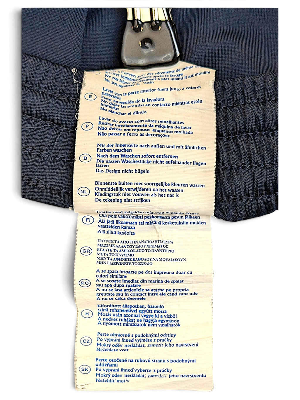JAKE & IPI Champion track pants care label with multi-language washing instructions on navy fabric