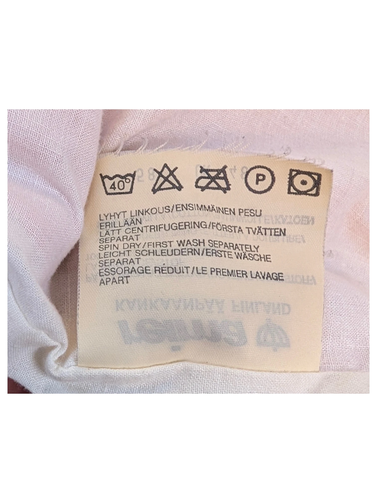 JAKE & IPI clothing care label with washing instructions in multiple languages including Finnish and English