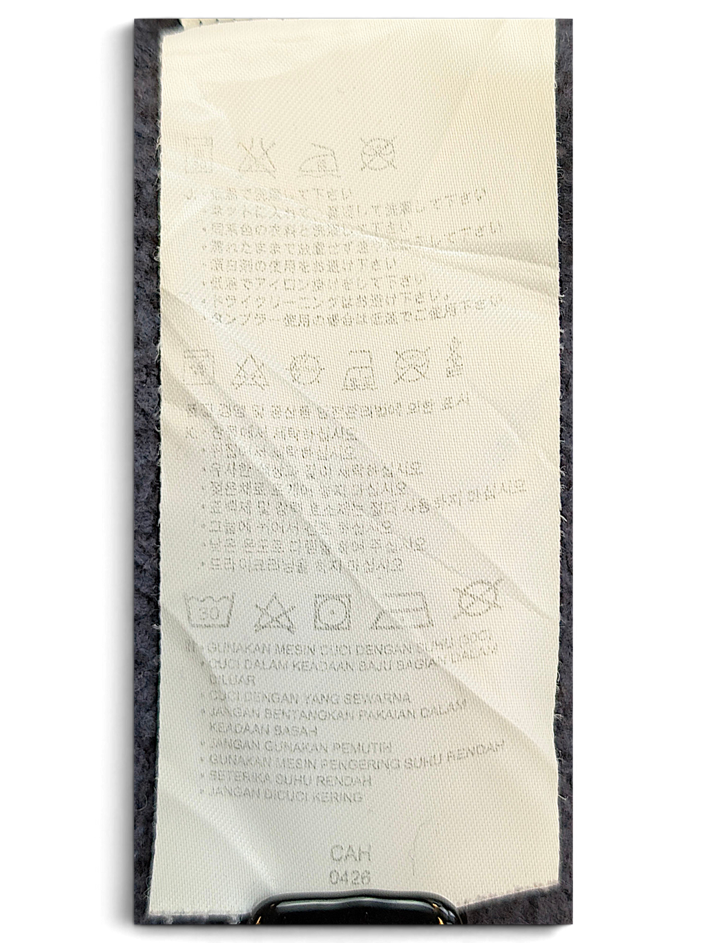 JAKE & IPI Converse Cropped College garment care label with washing instructions and symbols on a dark fabric background