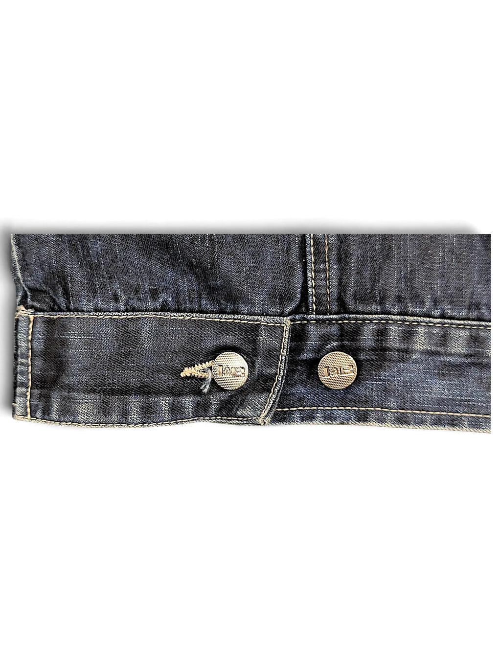 Close-up of the dark blue denim hem and branded metal buttons on a JAKE & IPI Johnny Blaze denim jacket.