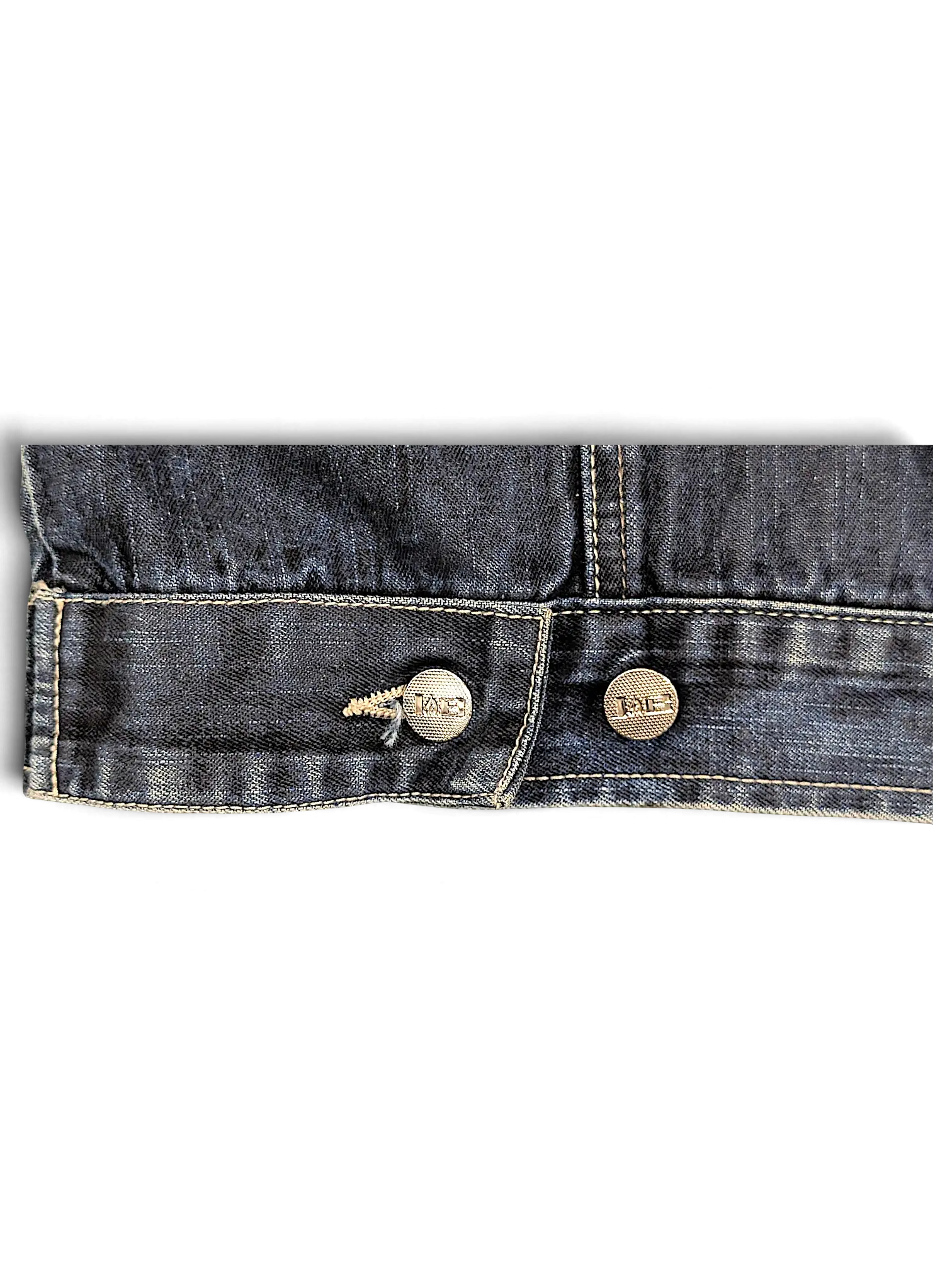 Close-up of the dark blue denim hem and branded metal buttons on a JAKE & IPI Johnny Blaze denim jacket.