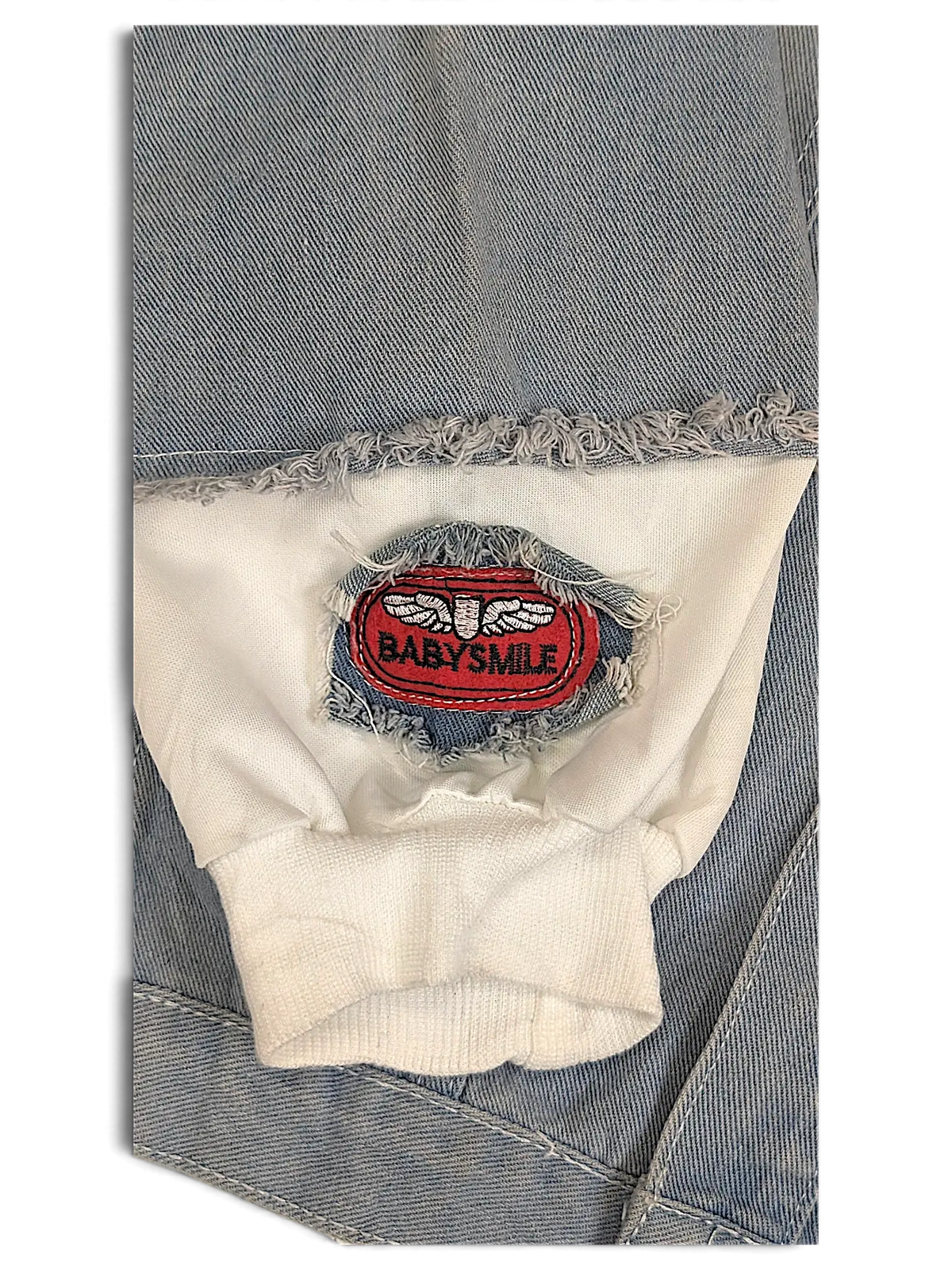 JAKE & IPI hooded denim jacket sleeve detail featuring a white ribbed cuff and a red Babysmile patch with frayed edges
