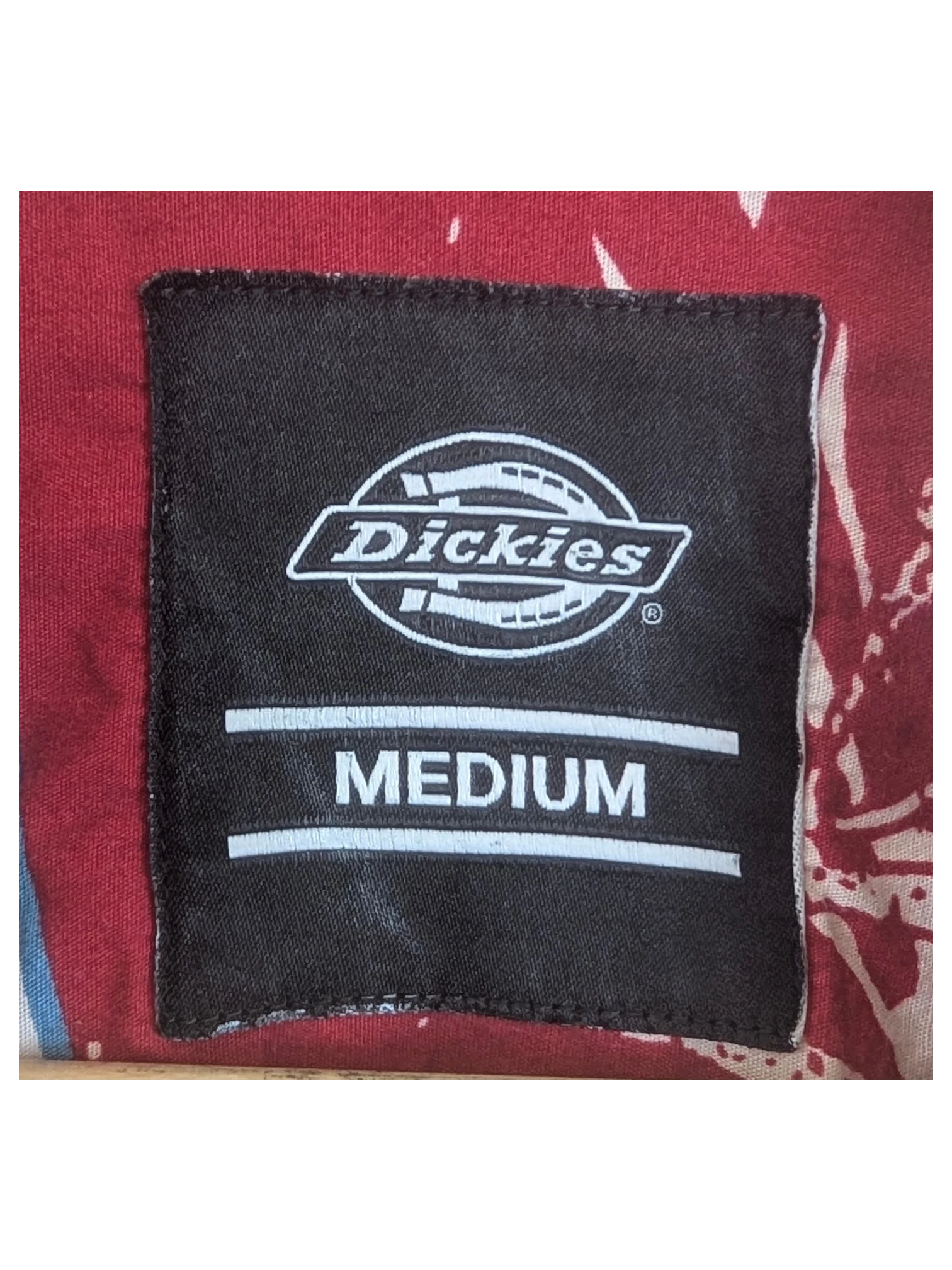 JAKE & IPI Dickies Hawaiian shirt in red with a floral pattern and a medium size neck label on a wooden hanger