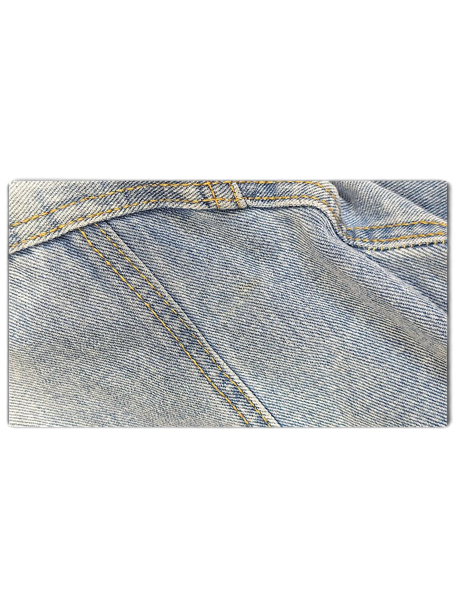 Close-up of JAKE & IPI light blue distressed denim jacket fabric with contrast yellow stitching