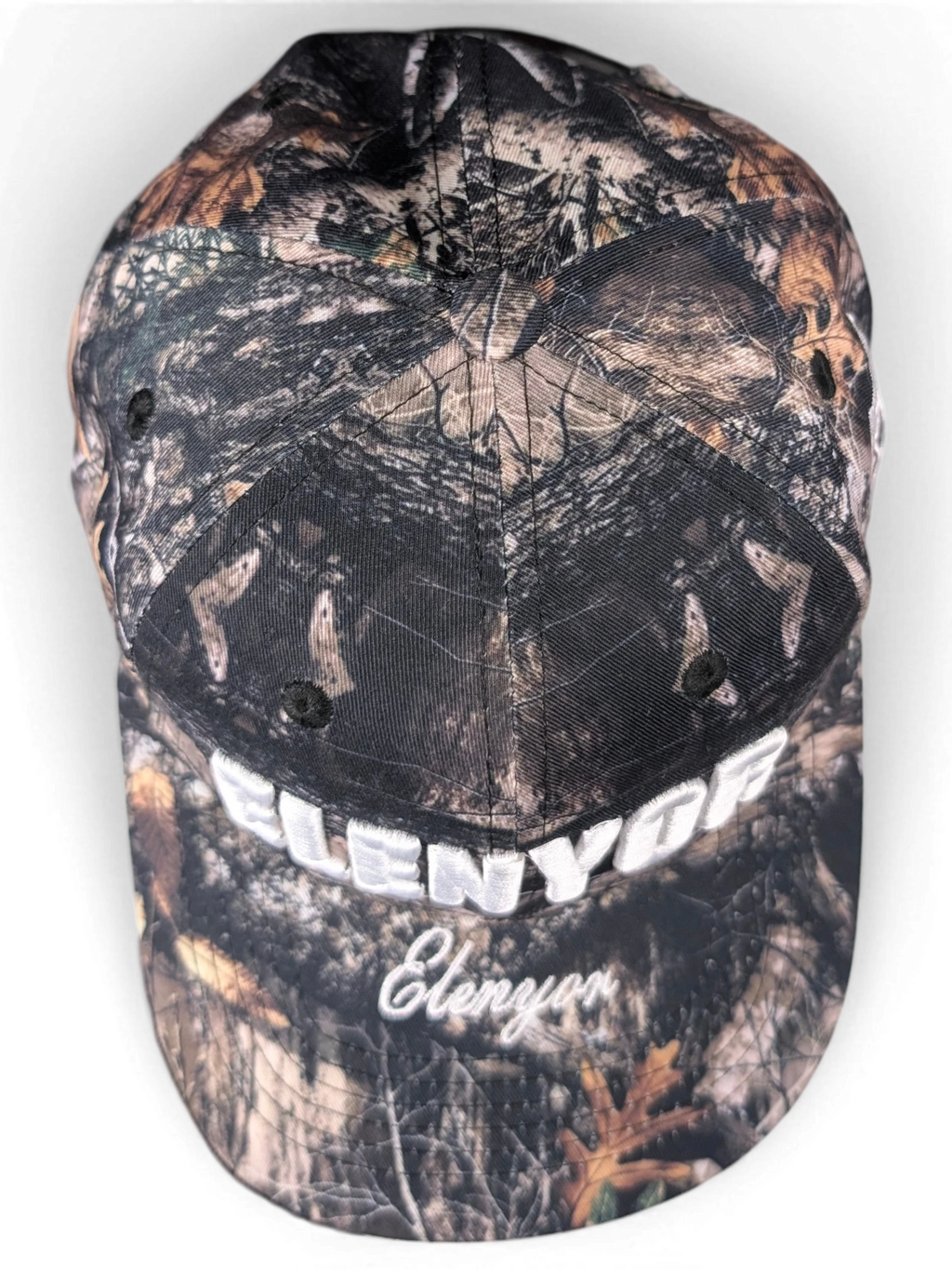 JAKE & IPI Elenyor baseball cap in a brown and black woodland camouflage print with white embroidered text