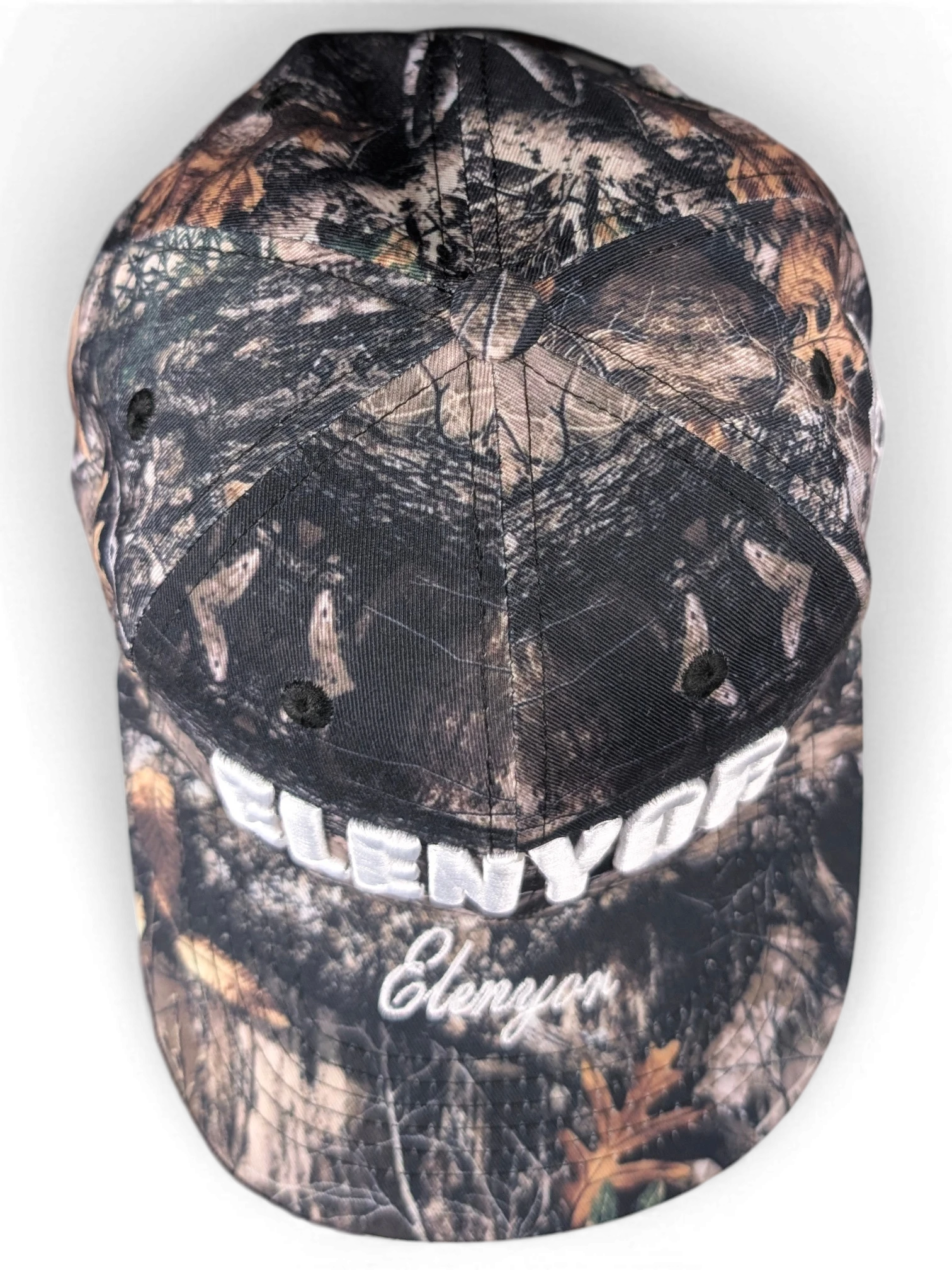 JAKE & IPI Elenyor baseball cap in a brown and black woodland camouflage print with white embroidered text