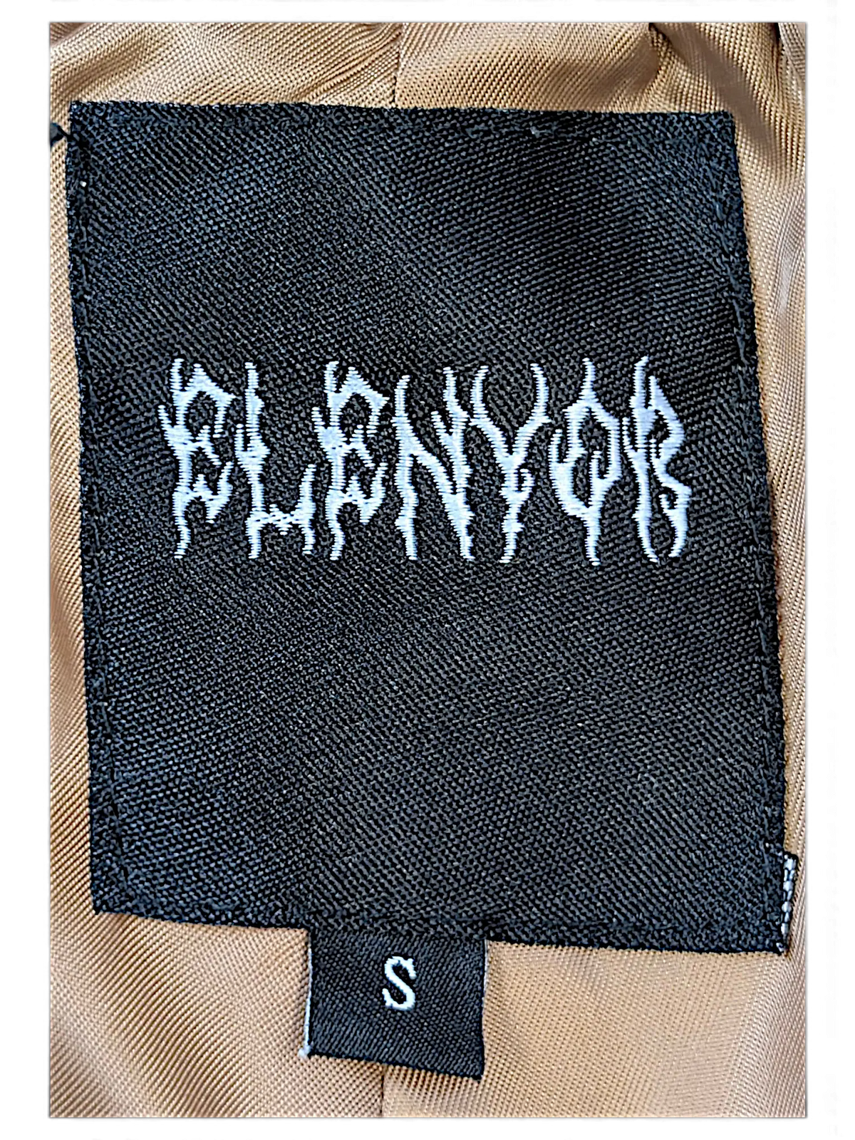 JAKE & IPI Elenyor brown jacket and pants clothing label with size S tag on a tan fabric background