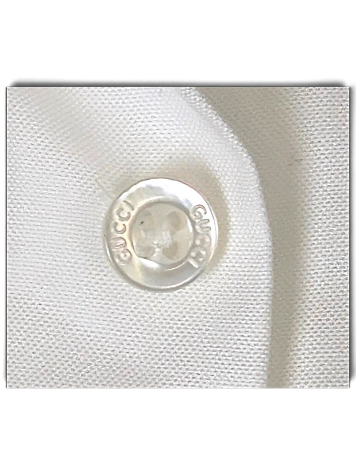 Close-up of a white JAKE & IPI Gucci shirt featuring a branded mother-of-pearl button with engraved Gucci logo.