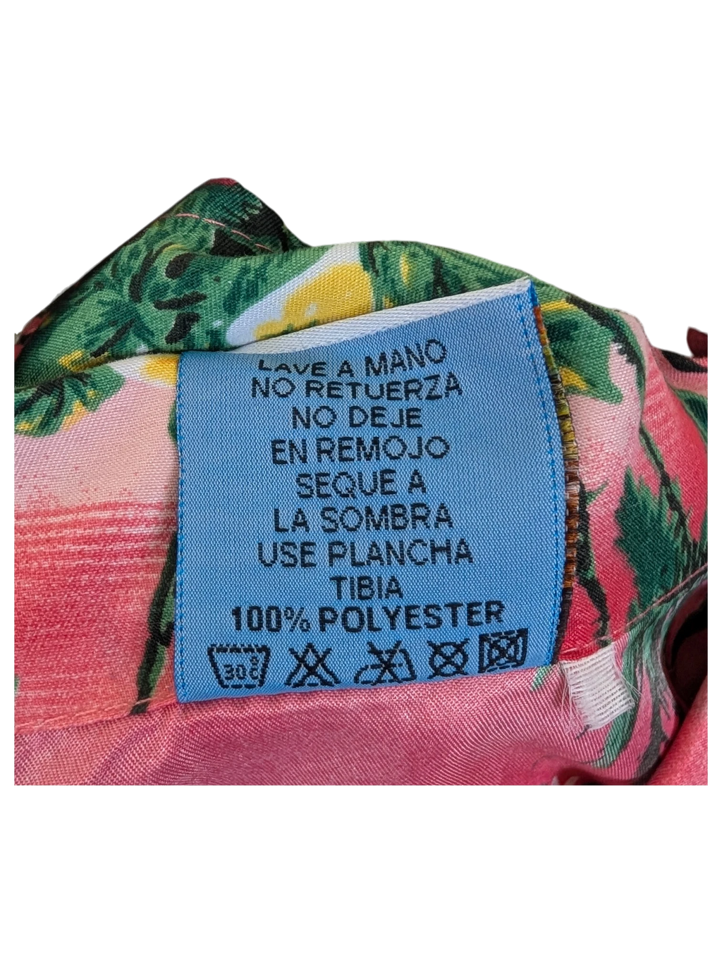 JAKE & IPI Hawaiian shirt care label showing 100% polyester material and washing instructions in Spanish