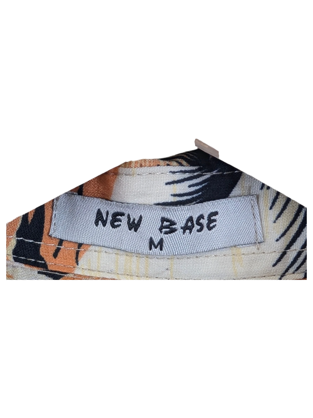 JAKE & IPI New Base Hawaiian shirt featuring a tropical floral pattern in orange, black, and cream on a hanger.