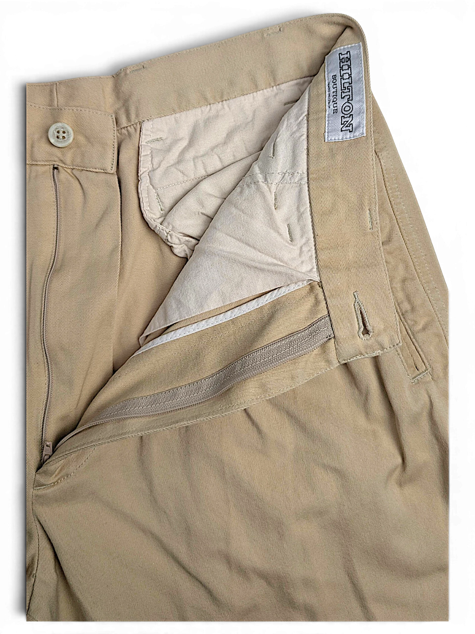 JAKE & IPI Hilton Boutique beige pleated trousers with a tailored waistband and zip fly closure.