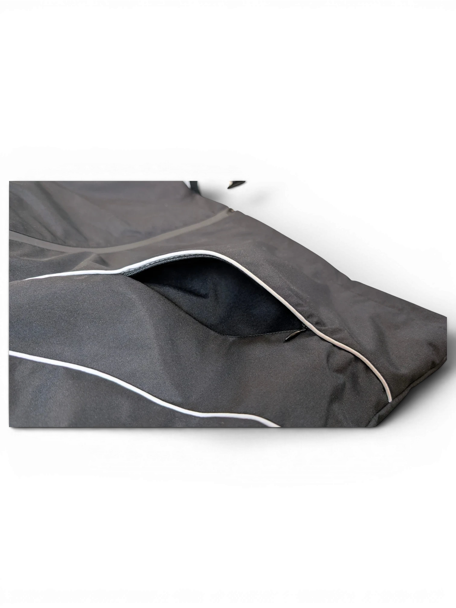 JAKE & IPI IBE Elenyor jacket featuring a black fabric exterior with reflective piping and a zippered pocket detail.