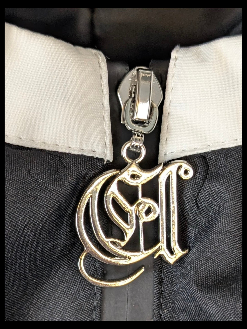 JAKE & IPI IBE Elenyor jacket featuring a detailed silver-tone metal logo zipper pull on a black and white fabric