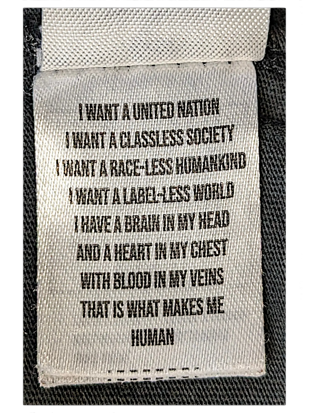 JAKE & IPI IBE Mori Velle long-sleeve shirt white fabric care label with black printed manifesto text