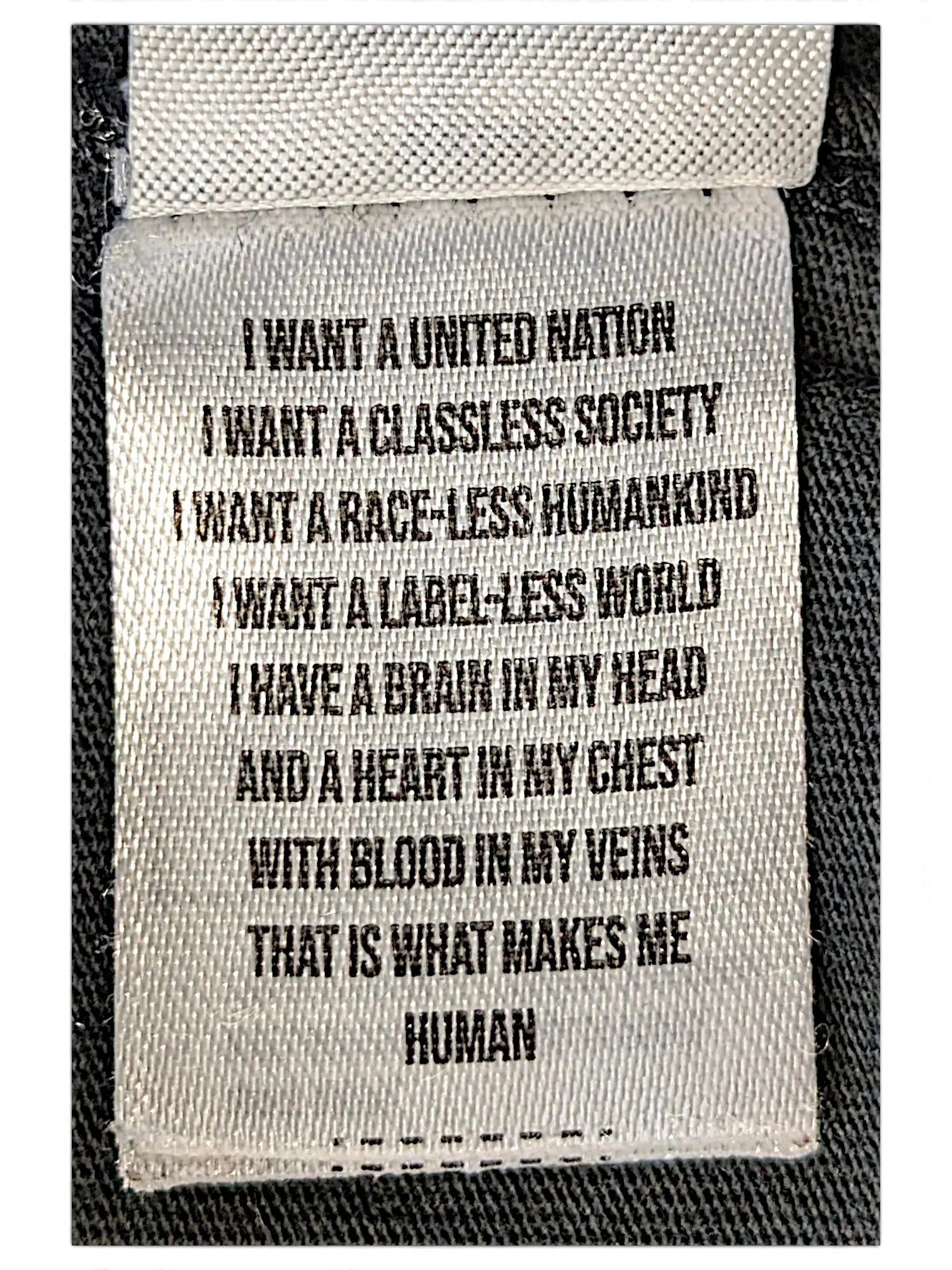 JAKE & IPI IBE Mori Velle long-sleeve shirt white fabric care label with black printed manifesto text