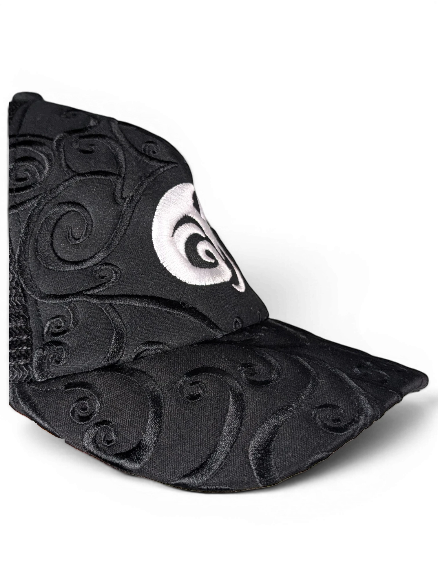 JAKE & IPI IBE Morivelle cap in black with intricate tonal embroidery and a prominent white circular logo detail