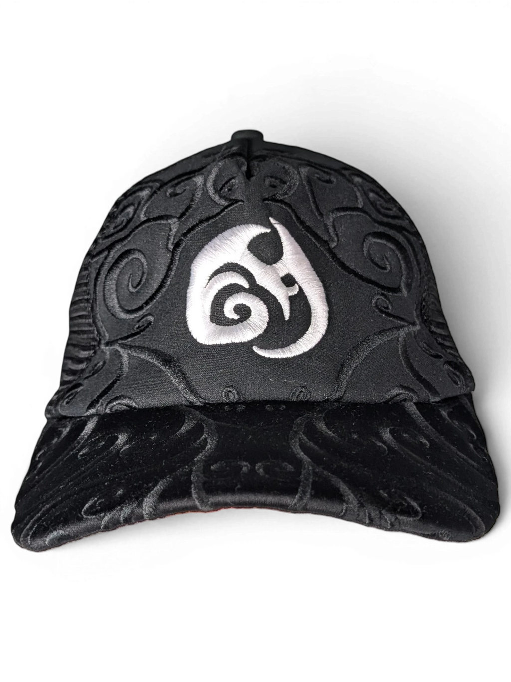 JAKE & IPI IBE Morivelle black cap with white embroidered logo and intricate tonal swirl patterns on the crown and brim.