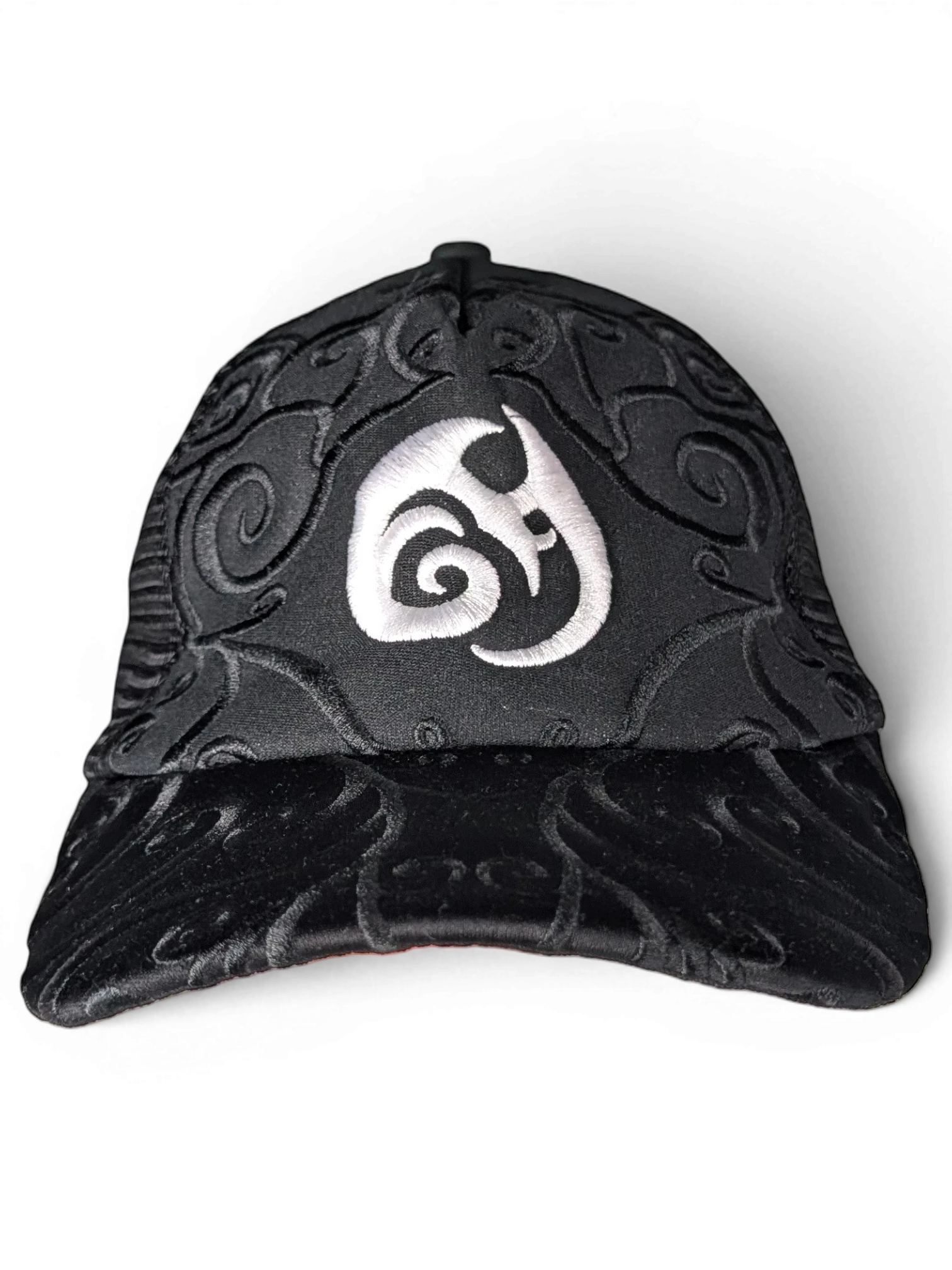 JAKE & IPI IBE Morivelle black cap with white embroidered logo and intricate tonal swirl patterns on the crown and brim.