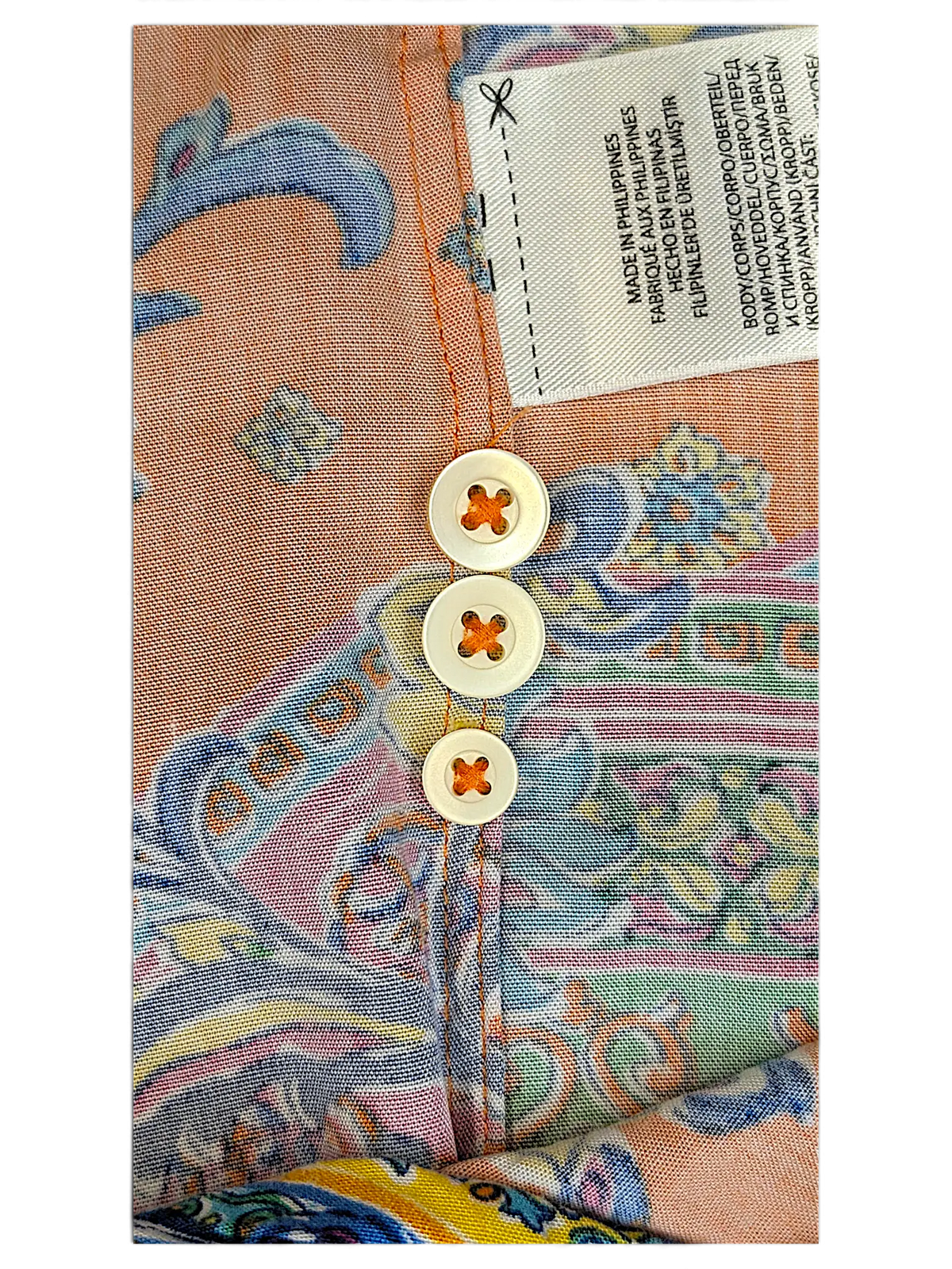 Close-up of JAKE & IPI IBE polo shirt featuring a vibrant multicolor paisley print and three white buttons.