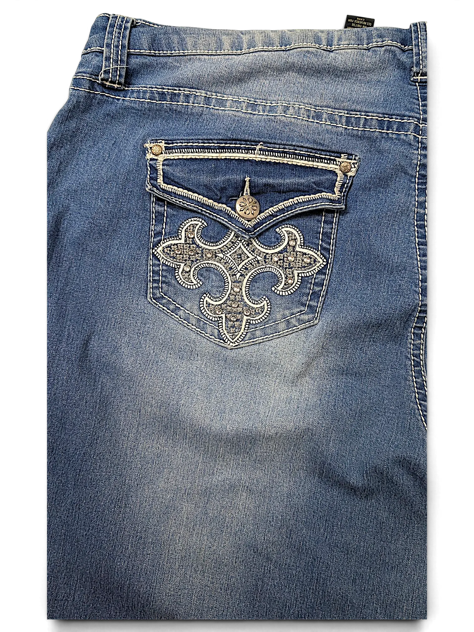 JAKE & IPI indigo Y2K jeans featuring a back pocket with intricate white embroidery, silver studs, and a button flap.