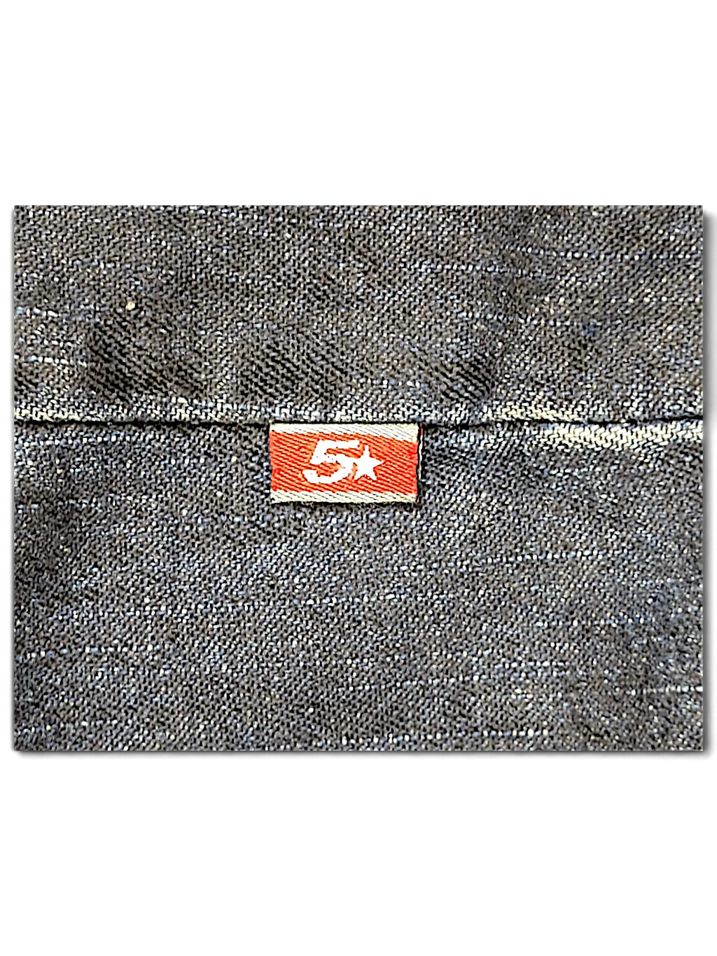 Close-up of JAKE & IPI Johnny Blaze dark blue denim jacket featuring a small red brand tag with a white star logo.