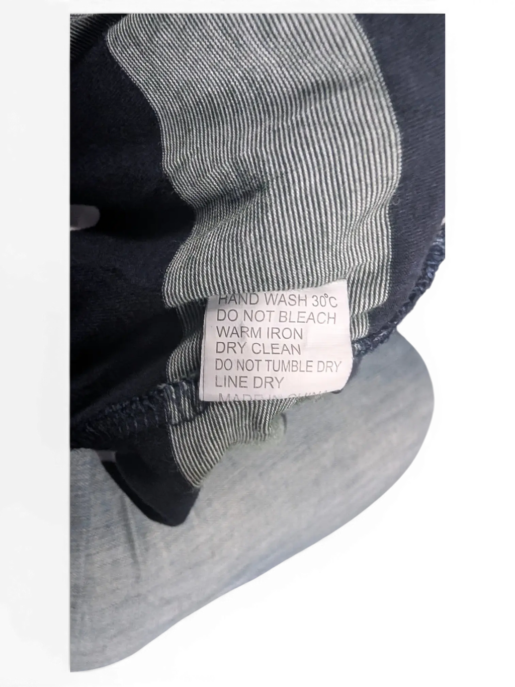 JAKE & IPI pre-owned Lacoste polo shirt care label with navy and grey striped fabric background