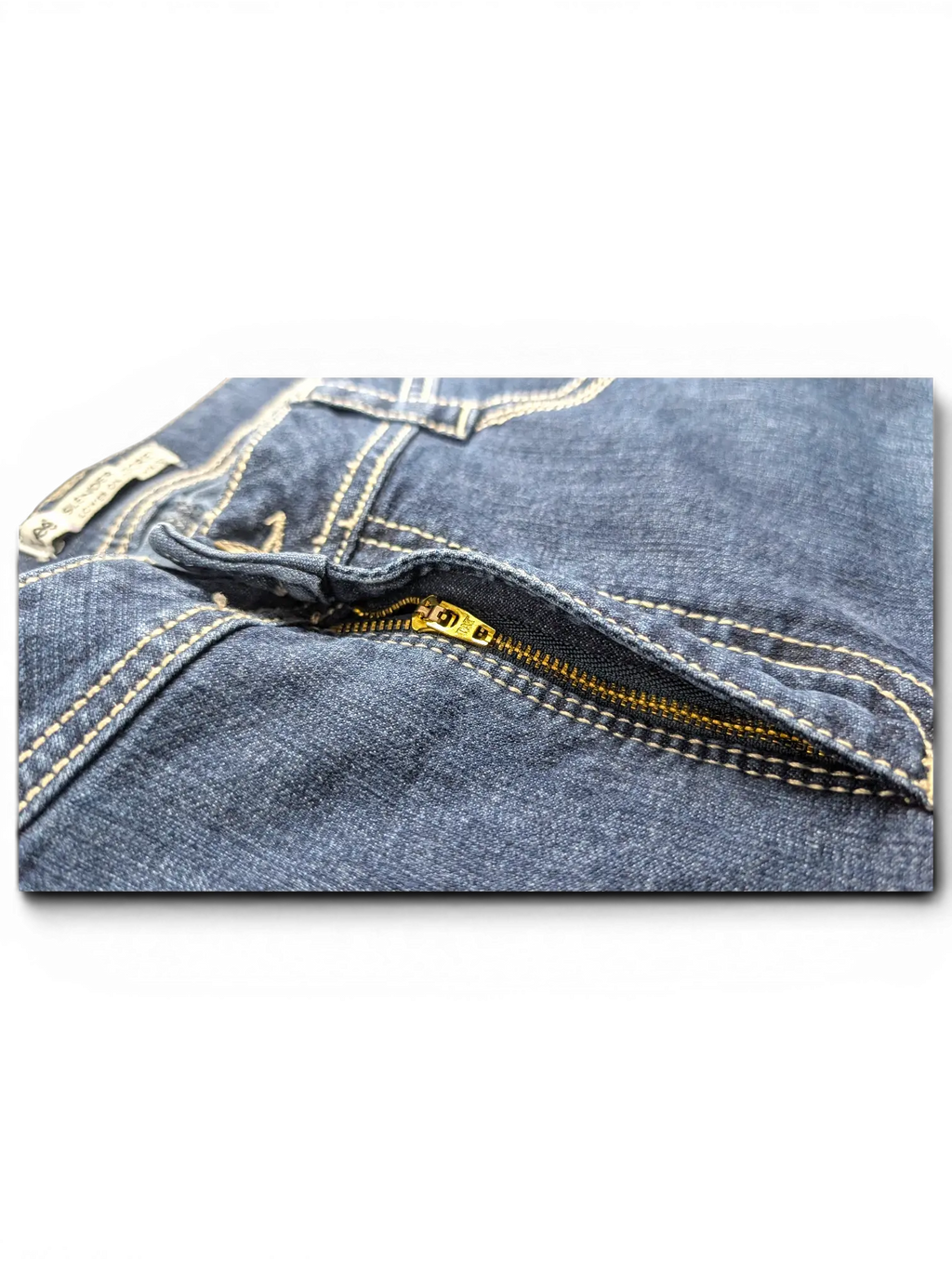 Close-up of JAKE & IPI Lee Slender Secret blue denim jeans featuring a gold metal zipper and contrast stitching.