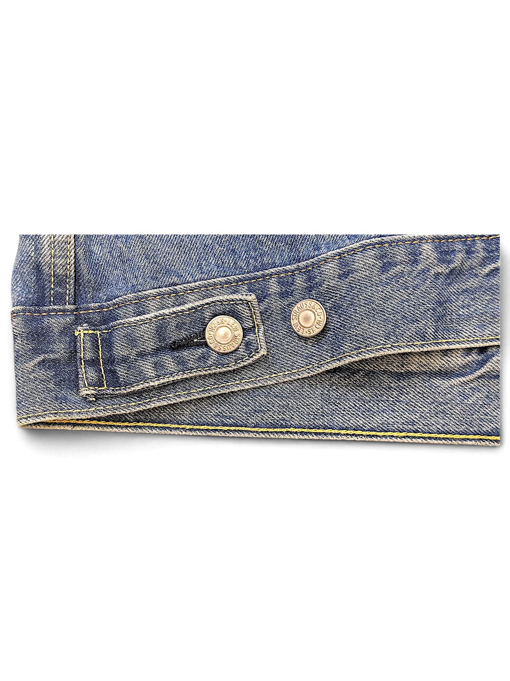 Close-up of the hem and metal button detail on a blue denim Levi's jacket from JAKE & IPI